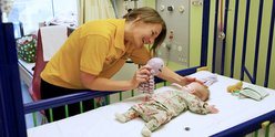 Volunteer member playing with GOSH patient in cot