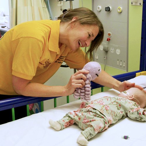 Volunteer member playing with GOSH patient in cot