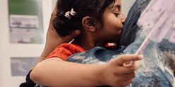 Little girl holding wand and kissing her mum on cheek