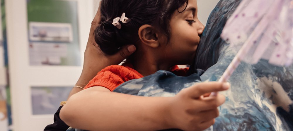 Little girl holding wand and kissing her mum on cheek
