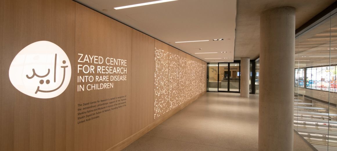 Photo taken inside the ZCR. Logo on the wall alongside sign reading Zayed Centre for Research into Rare Disease in Children