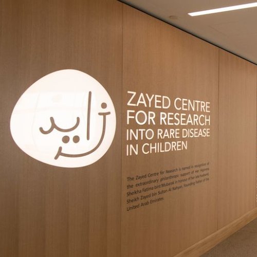 Photo taken inside the ZCR. Logo on the wall alongside sign reading Zayed Centre for Research into Rare Disease in Children