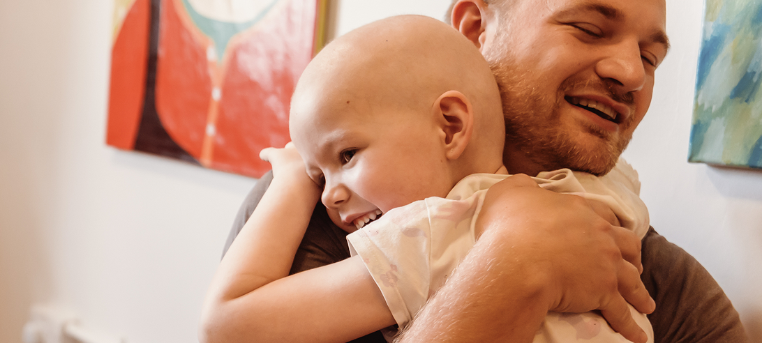A child smiling and hugging her dad.