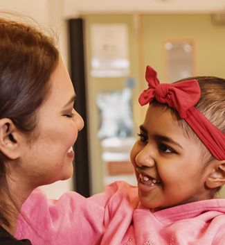 Girl wearing red hairband smiles at her mum