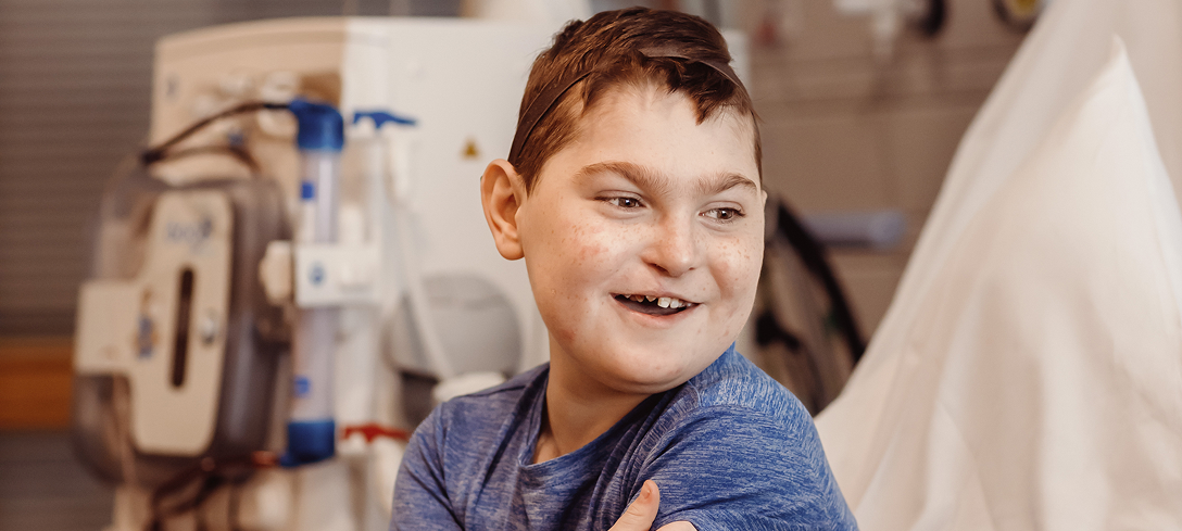 Boy sitting on hospital bed, smiling
