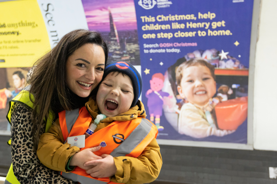 Henry with his mum standing in front of a Christmas tube ad that he features in